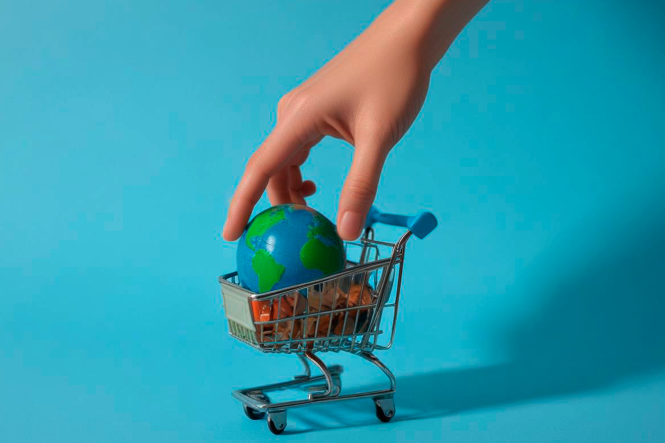 Imagen de una mano que deposita un globo terráqueo dentro de un carro de súper miniatura 